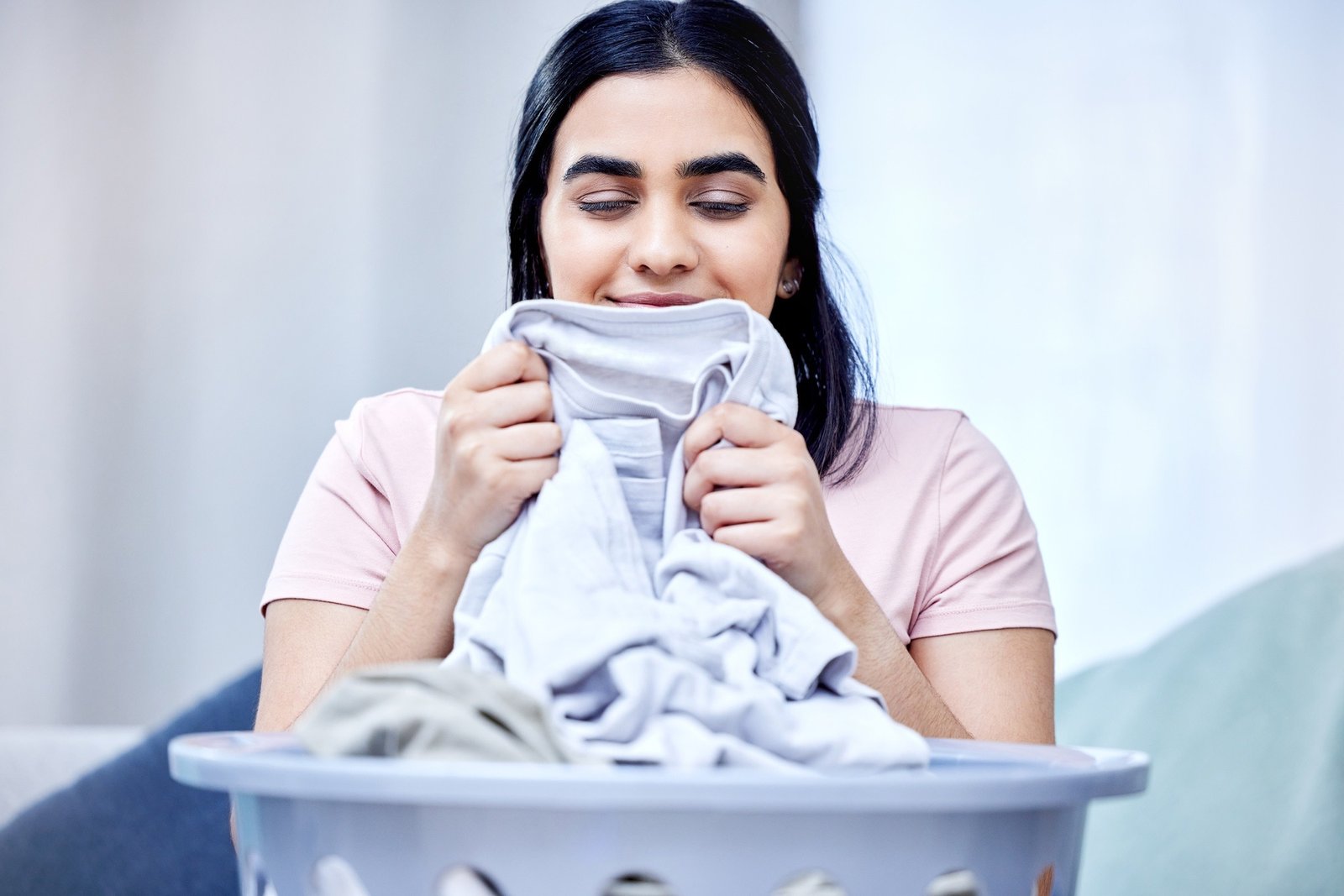 I love the smell of freshly washed clothes. Shot of a young woman doing laundry at home.